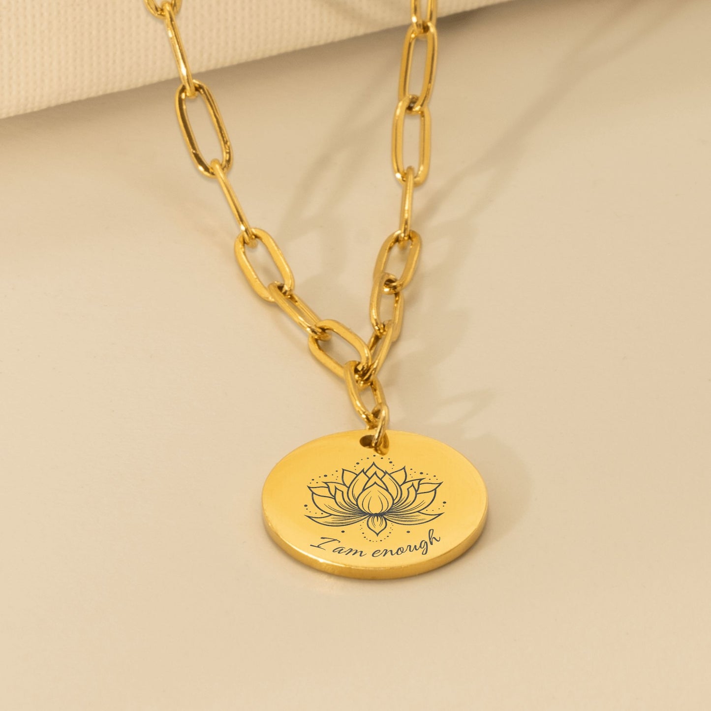 Close up van gouden affirmatieketting met gravure I am enough en lotusbloem – sieraad voor zelfliefde, zelfacceptatie en innerlijke rust